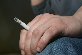 man drinking from a bottle and holding a cigarette between his fingers